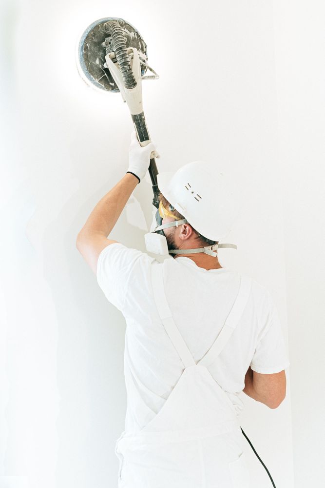 Decorator sanding a ceiling with a power sander