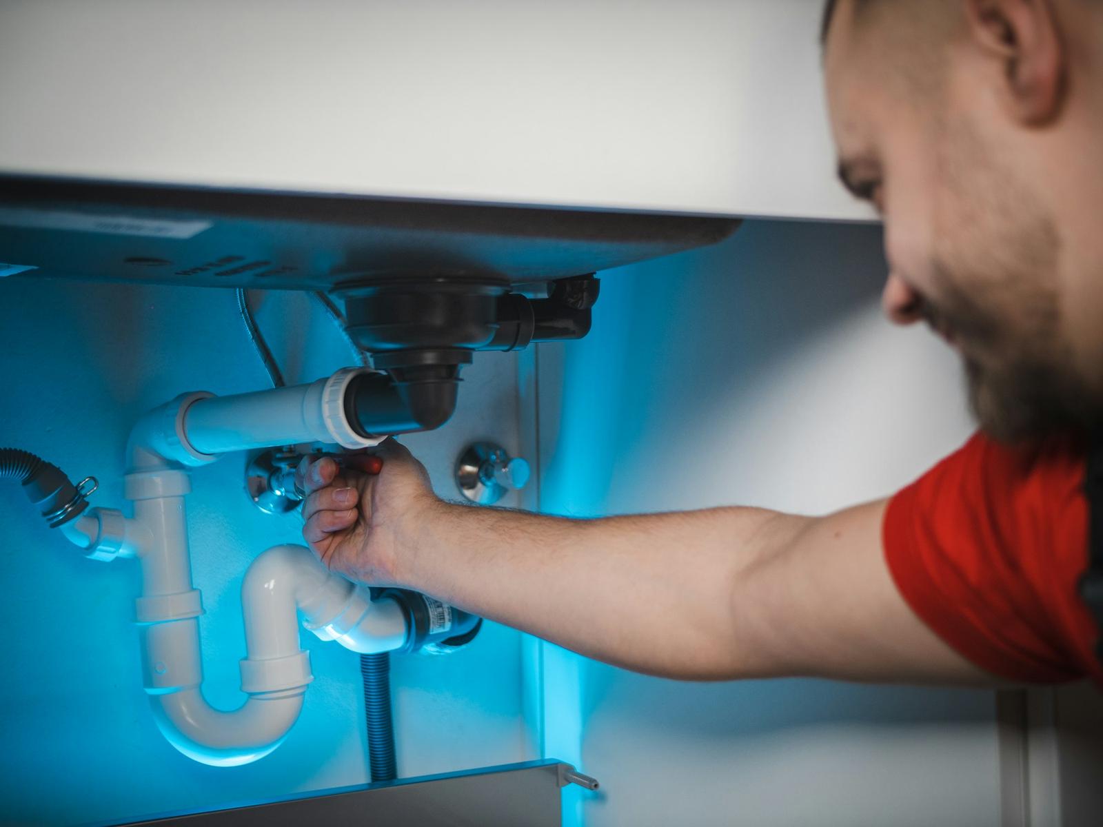 Plumber fitting a waste pipe under a kitchen sink
